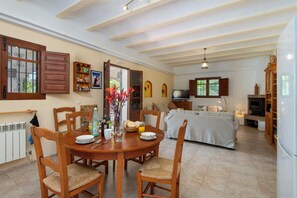 Un vaste espace dédié à la salle à manger, avec une table ronde en bois, des chaises et un vase rempli de fleurs.