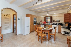 A compact kitchen with wooden cabinets, a white refrigerator, and a dining area with a table and chairs.