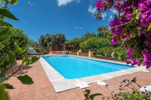 Une piscine avec des chaises longues et une structure en bois en arrière-plan.
