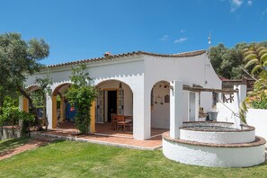 Un bâtiment blanc avec un toit en tuiles, de nombreuses arcades et une petite cour intérieure agrémentée d’une fontaine.