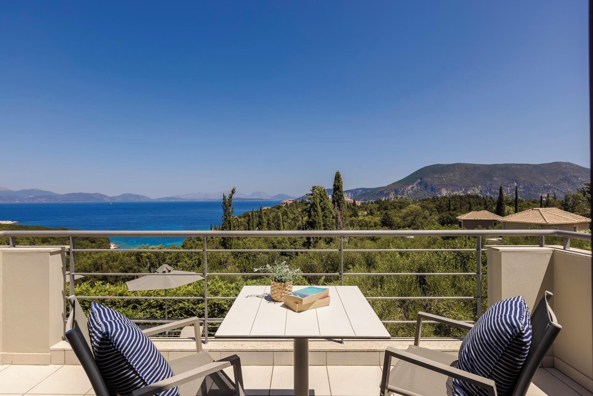 Una terraza con mesa y sillas, con vistas al mar y montañas a lo lejos.