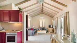Cozinha espaçosa com fogão vermelho, sala de jantar com mesa de vidro e sala de estar com sofá e televisão.