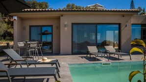 Ein modernes Gebäude mit Pool, Liegestühlen und einem Tisch mit Stühlen.