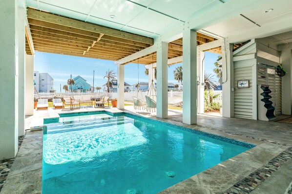 A swimming pool with a wooden deck and a view of houses in the background.