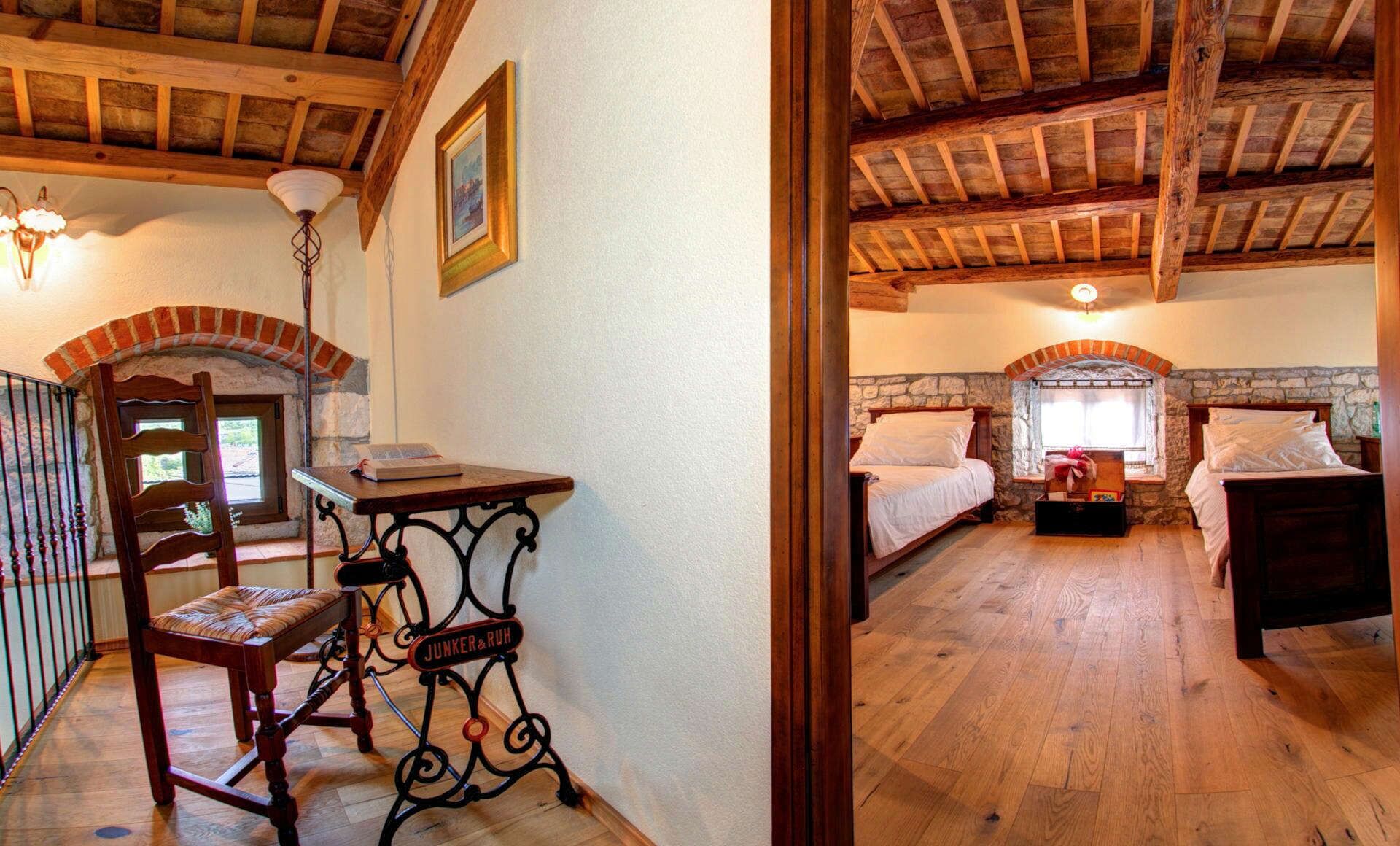 Una habitación rústica con techo de madera, pared de piedra y cama con chimenea de piedra.