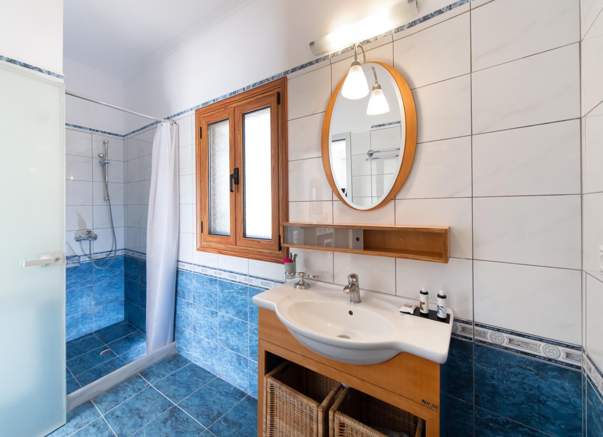 A bathroom with a shower, a sink, a mirror, and a window.