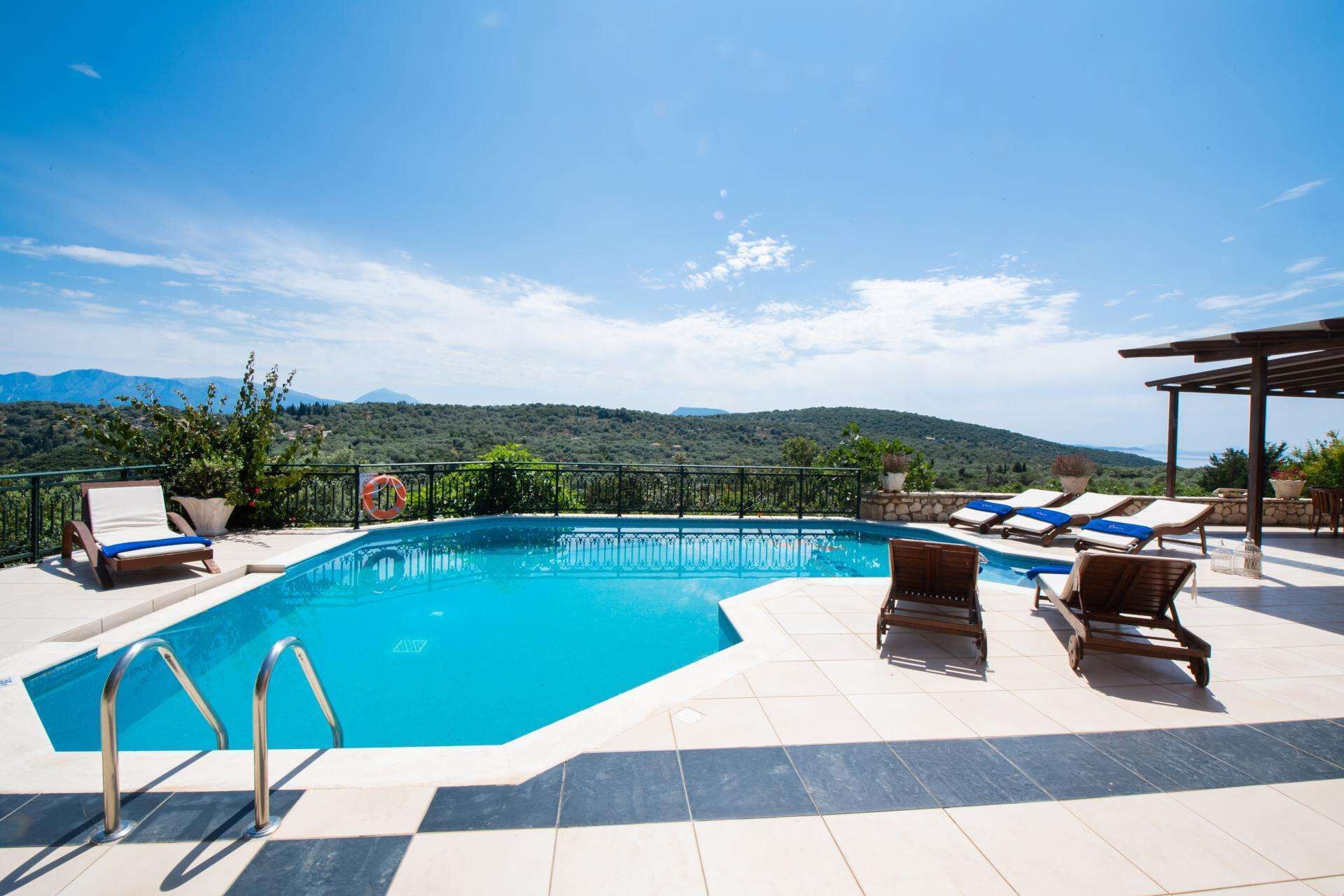 A swimming pool with lounge chairs and a view of mountains.
