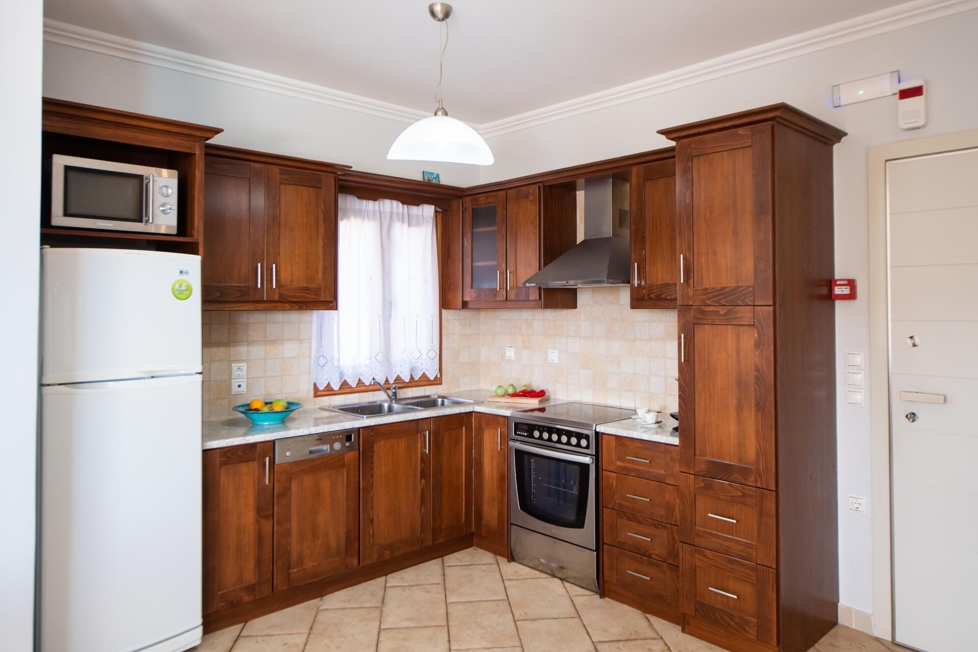 A kitchen with wooden cabinets, a microwave, a refrigerator, a sink, and an oven.