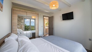 Un dormitorio con una cama grande, un televisor montado en la pared y vistas al exterior a través de una puerta.