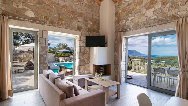 Amplia sala de estar con pared de piedra, piscina y balcón con vistas.
