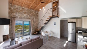 Un interior moderno con pared de piedra, techo de madera, una escalera, un comedor y una cocina.