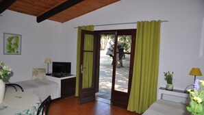 Una stanza con un letto, una scrivania con un computer, una TV e una finestra con tende.