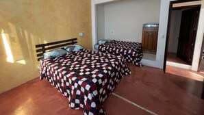 Ein Zimmer mit zwei Betten, einem Holzschrank und einem Spiegel an der Wand.
