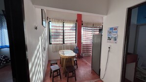 Ein kompakter Wohnraum mit rundem Tisch und Hockstühlen, einem Kühlschrank und einem Wasserspender.