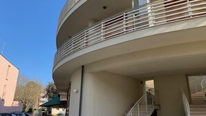 A multi-level building with a curved balcony, a staircase, and a parked car. - Elegant apartment in the seaside park in Marina Centro (Rimini)