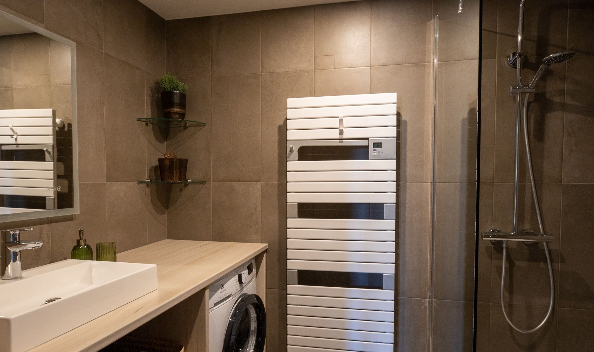 Een moderne badkamer met een wastafel, spiegel en een ingebouwde wasmachine.