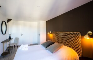 Una camera d'albergo con un letto, una scrivania, una sedia e una lampada a parete.