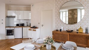 Una cocina moderna con armarios blancos, un comedor con un espejo redondo y una zona de buffet.