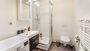 Un baño moderno con ducha de vidrio, inodoro y lavadora.