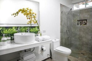 A modern bathroom with a white sink, toilet, and glass-enclosed shower. - 50N15 B&B (Cali)
