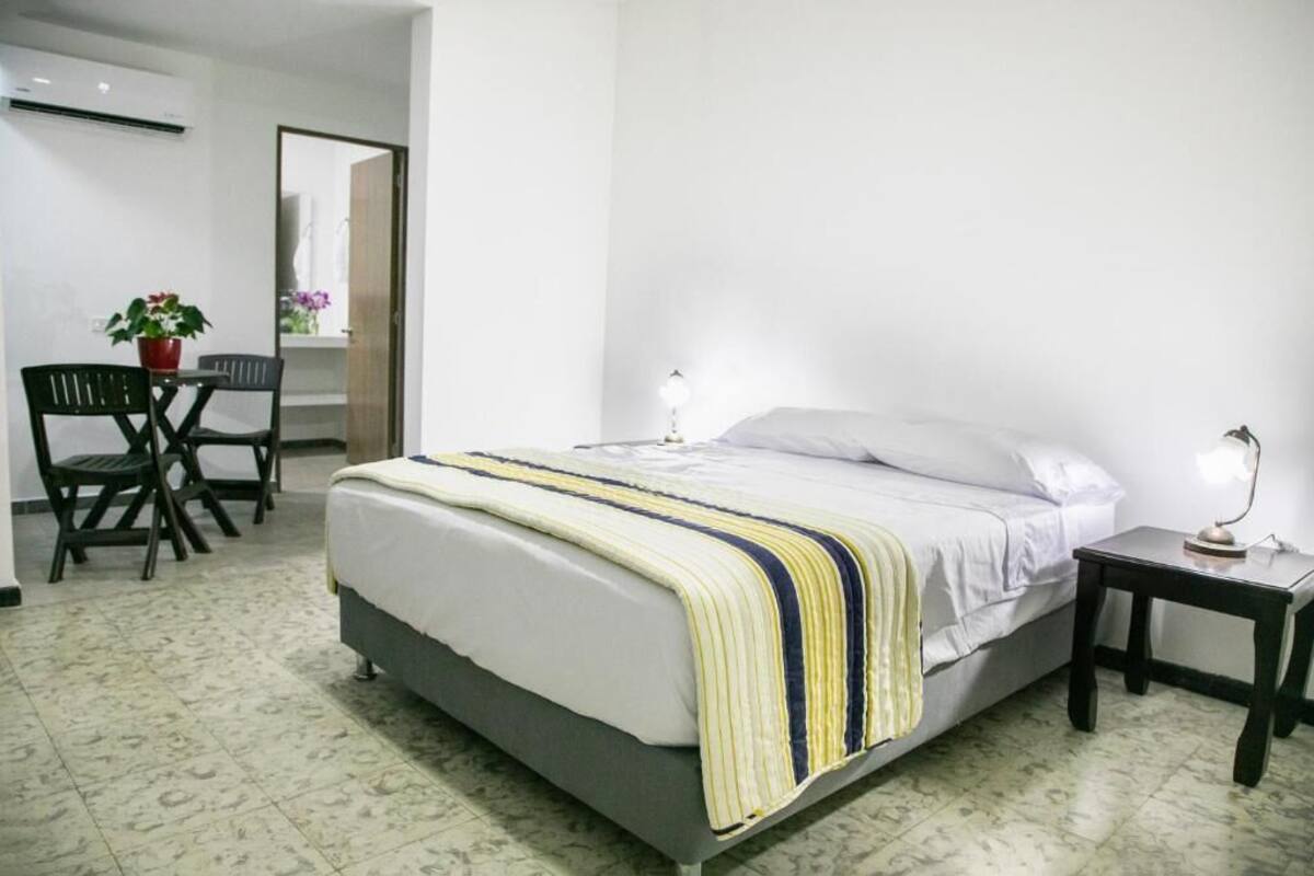 A bedroom with a bed, bedside tables, a chair, and a potted plant.