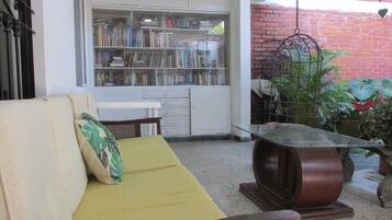 A cozy living area with a sofa, a small table, and a bookshelf filled with books.