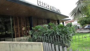 A restaurant named "Crepes & Waffles" with a modern facade, wooden slats, and a well-maintained garden area. - 50N15 B&B (Cali)