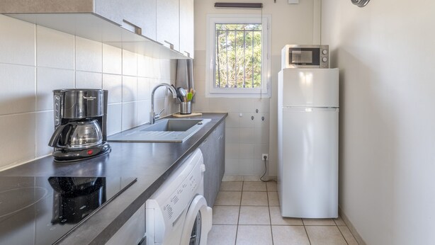 Uma cozinha compacta equipada com cafeteira, micro-ondas e frigorífico.