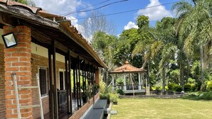 Un espacio al aire libre techado con pared de ladrillo, piso de madera y un pequeño pabellón.