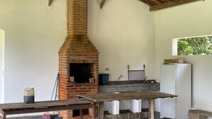 Una cocina rústica con un horno de ladrillo, un lavamanos y un refrigerador.