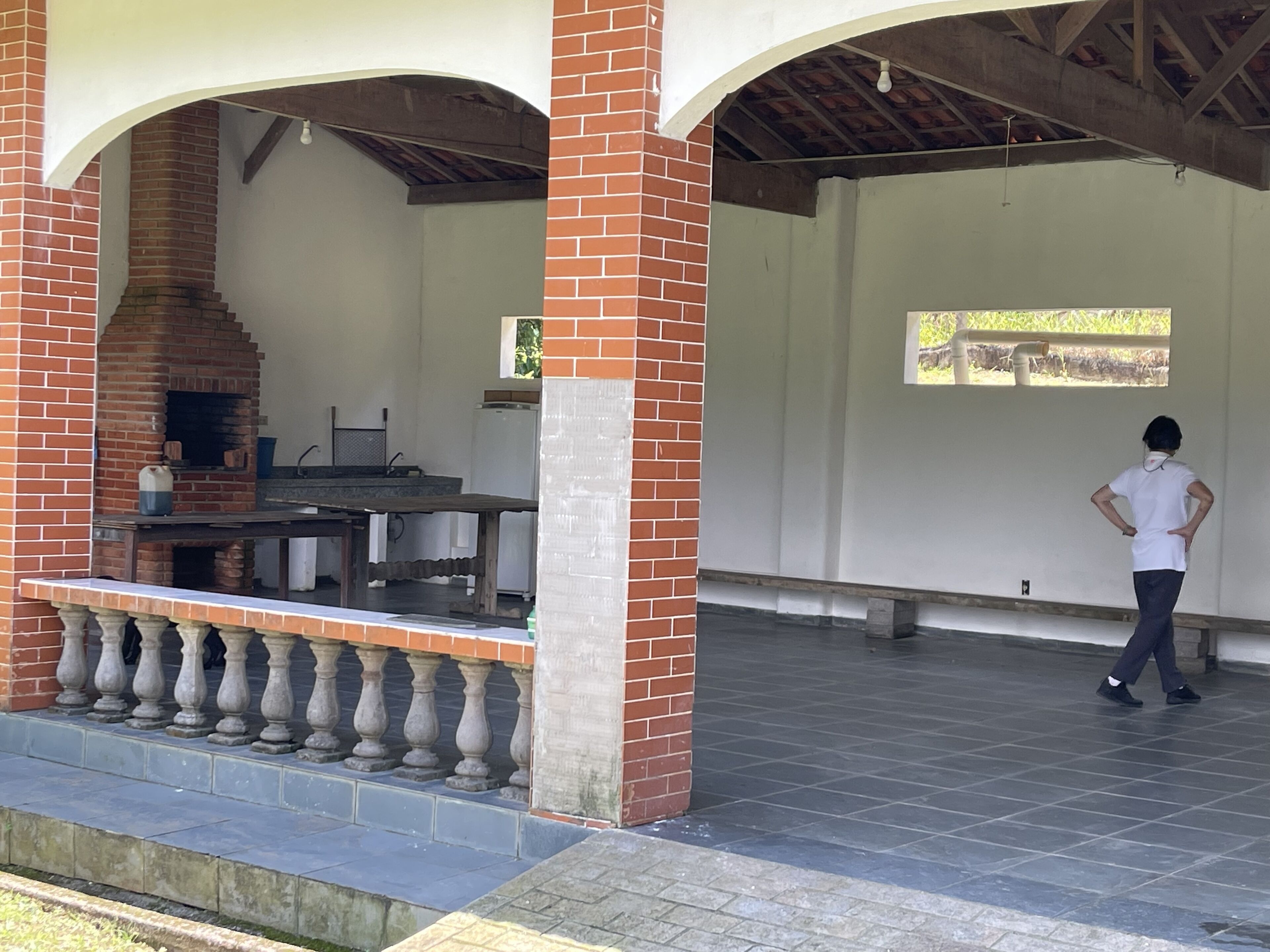 An outdoor covered area with a brick barbecue and a table.