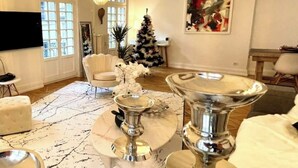 Un vaste salon agrémenté d’un grand lustre, d’un sapin de Noël et d’un téléviseur à écran plat fixé au mur.