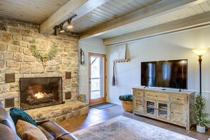 Una chimenea de piedra, un televisor, un armario de madera y un sofá en una sala de estar.