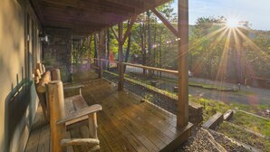 A wooden deck with benches, a stone wall, and a view of a road and trees. - Beech Mtn: Walk to Slopes, Sleeps 9, Pet Friendly, Mountain Views, Cozy Retreat (Beech Mountain)