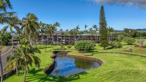 Um hotel com piscina, rodeado por palmeiras e um campo de golfe.