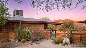 A brick building with a metal roof, surrounded by various cacti and desert plants. - Spacious casita with desert & mountain views ⛰ (Tucson)