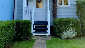 A two-story house with a front porch, a palm tree, and a wreath on the door. - Peaceful Lakefront Escape w/ Deck & Views (South Cerney)