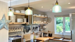 A modern kitchen with wooden countertops, stainless steel appliances, and pendant lighting. - Peaceful Lakefront Escape w/ Deck & Views (South Cerney)