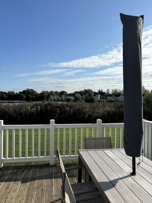 Une terrasse en bois avec une balustrade blanche, une table et une chaise.