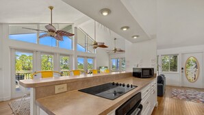 A modern kitchen with a central island, overhead fans, and large windows. - Kayak Cove: Bayfront with dock - A paddle in / paddle out resort (Cedar Key)