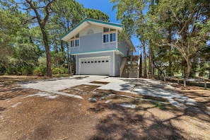 A two-story house with a garage, surrounded by trees.