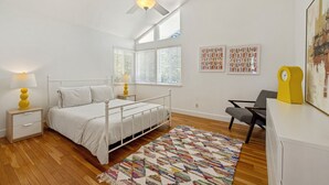 A bedroom with a bed, bedside tables, a ceiling fan, a desk, and a chair. - Kayak Cove: Bayfront with dock - A paddle in / paddle out resort (Cedar Key)
