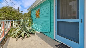 A turquoise house with a sun mural, a blue door, and a concrete porch.