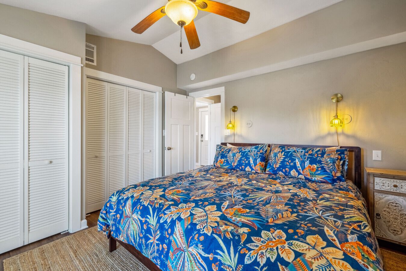 A bedroom with a bed, a ceiling fan, a wardrobe, and a nightstand.