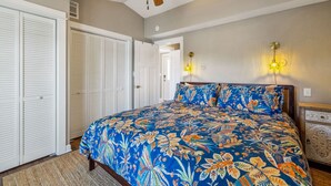 A bedroom with a bed, a ceiling fan, a wardrobe, and a nightstand.