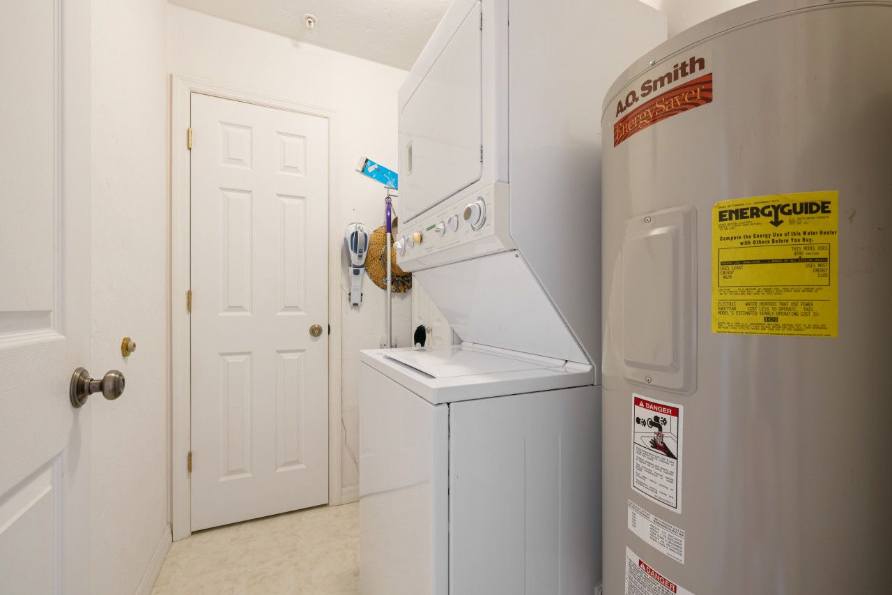 Un cuarto de lavandería con una lavadora y secadora blancos, una puerta y una etiqueta ENERGY GUIDE en la secadora.