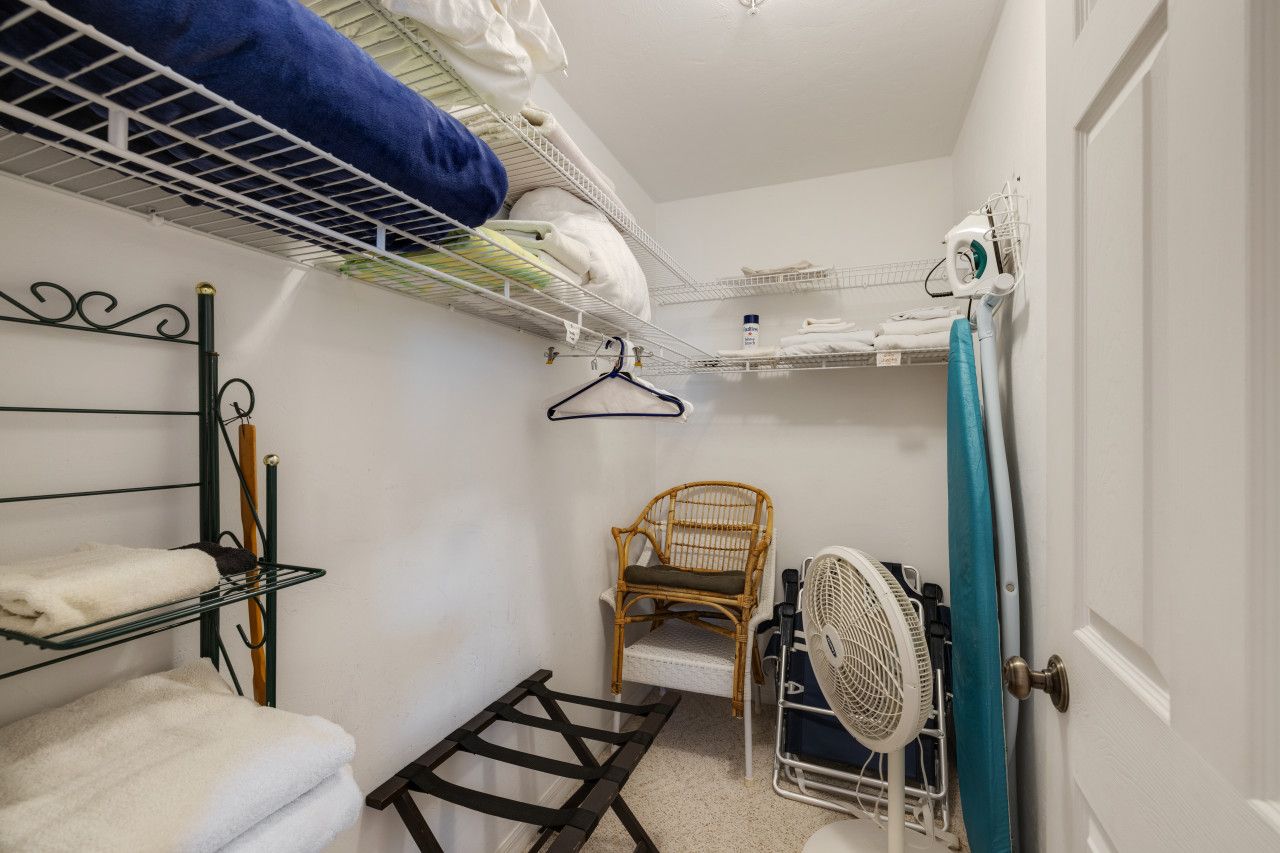 A compact room with bunk beds, a chair, a fan, and a drying rack.