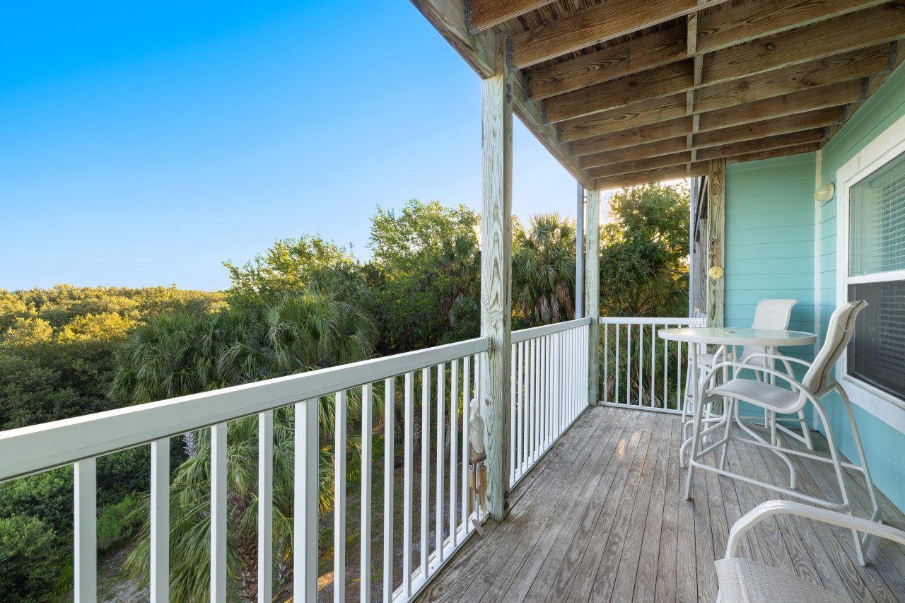 A wooden deck with a white railing, a table, and chairs.