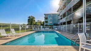 A swimming pool with a no diving sign, surrounded by white chairs and a metal fence, with a multi-story building in the background. - Above the Rest B301:  A spacious penthouse with water views (Cedar Key)