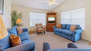 A living room with two blue sofas, a wooden cabinet, and a ceiling fan. - Above the Rest B301:  A spacious penthouse with water views (Cedar Key)